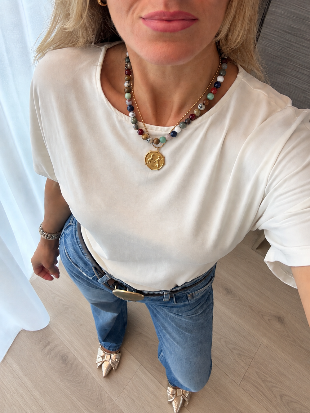 a woman wearing a necklace and jeans