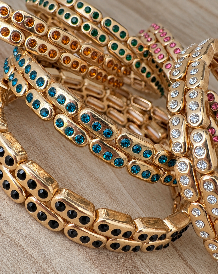 a group of gold bracelets with colorful stones