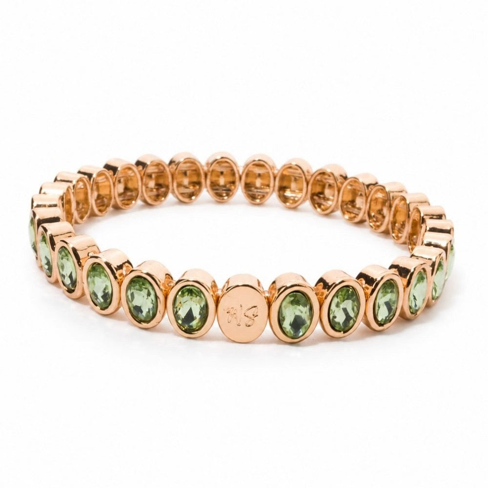 a gold bracelet with green stones