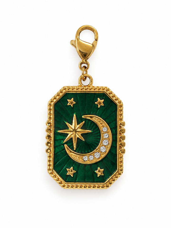 a green and gold pendant with a moon and stars