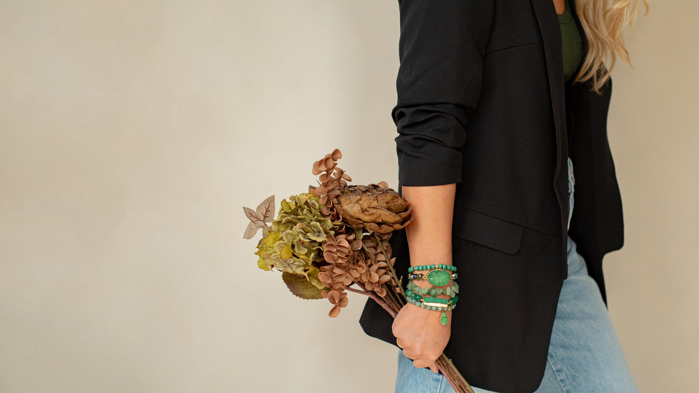 Person holding a bouquet of dried flowers against a plain background